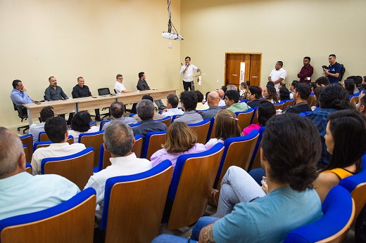 Imagem: No Auditório do Campus de Itapajé, o reitor Custódio Almeida (de branco, no púlpito, à direita) discursa; à sua esquerda, estão as autoridades da mesa solene; em primeiro plano, de costas e ocupando as cadeiras do auditório, o público presente ao evento. (Foto: Viktor Braga/ UFC Informa)