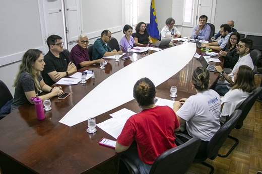 Imagem: Sentados em uma mesa marrom oval, representantes da administração e do comando de greve tratam das reivindicações de movimento da categoria técnico-administrativa. (Foto: Álvaro Graça Jr./ UFC Informa)