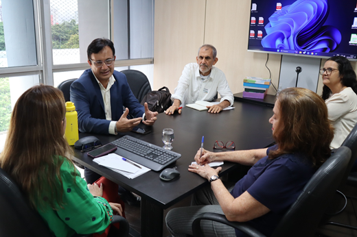 Imagem: Sentados à mesa, estão a secretária de Educação Eliana Estrela (de costas), o reitor Custódio Almeida e os demais participantes da reunião. (Foto: Rogério Bié/ Ascom SEDUC)