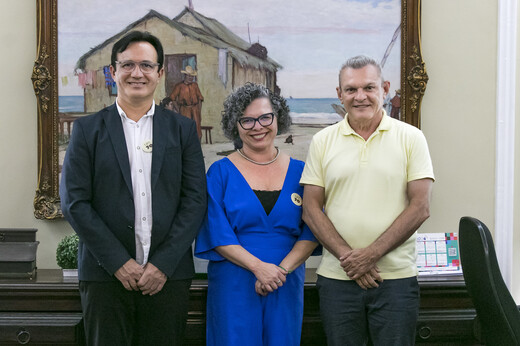 Imagem: Prof. Custódio Almeida (reitor), Profa Diana Azevedo (vice-reitora) e José Narto (prefeito de Fortaleza) posam, de pé, no Gabinete da Reitoria. Atrás, um quadro de Raimundo Cela. (Foto: Álvaro Graça Jr./ UFC Informa)