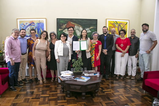 Imagem: Particioantes da assinatura do acordo posam, de pé, no Gabinete da Reitoria; ao centro, estão o reitor Custódio Almeida, a primeira-dama Lia Freitas e a vice-reitora Diana Azevedo. (Foto: Nilson Filho/ UFC Informa)