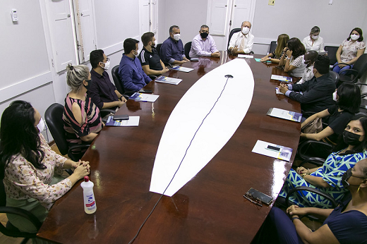 Participantes da cerimônia acompanham posse dos novos servidores sentados em uma mesa