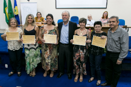 Foto do reitor Cândido Albuquerque ladeado por servidores com os certificados de gratidão por tempo de serviço 