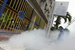 Foto de uma pessoa fazendo o serviço de "fumacê" na Universidade