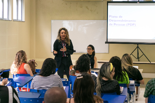 Imagem: Palestrante fala a um grupo de pessoas sentadas 