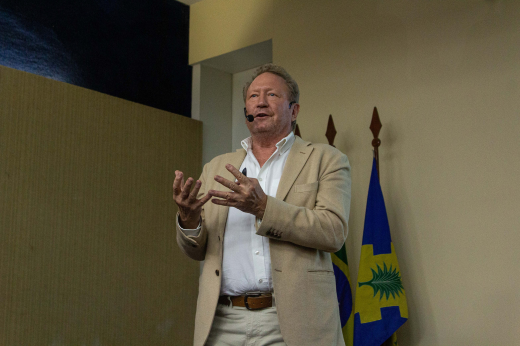 Imagem: Foto do palestrante Andrew Forrest em pé vestindo um terno bege e camisa social cinza sem gravata