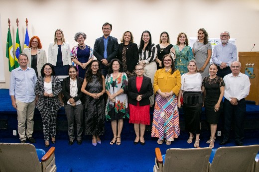 Grupo fotografado em duas fileiras horizontais, com a mesa do auditório da Reitoria da UFC ao fundo. Na fileira de trás, mais alta, estão a vice-reitora Diana Azevedo, o reitor Custódio Almeida e a presidente da ABMCJ, Ana Paula de Holanda