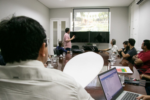 Imagem: Foto da perspectiva de quem vê a tela projetada na sala de reuniões com imagens do projeto arquitetônico da Estação Científica de Jeri