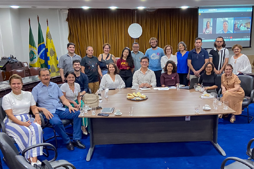 Imagem: grupo de pessoas das comissões organizador e eleitoral da Constituinte sentadas ou em pé ao redor de uma grande mesa na sala dos Conselhos da UFC