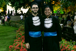 Imagem: Vestindo becas de faixa azul, os concludentes do Curso de Jornalismo Eldo Pereira e Felipe Mendes chegaram juntos à Concha Acústica (Foto: Viktor Braga/UFC)