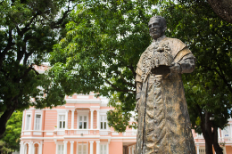 Imagem da estátua do Prof. Martins Filho com reitoria atrás