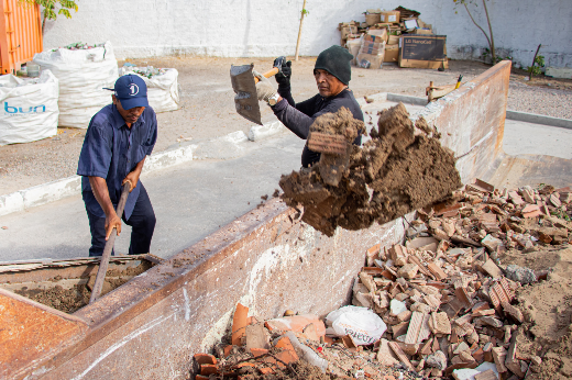 Imagem: Foto vista de cima mostra uma caçamba, com dois carroceiros do lado de fora, jogando entulhos com uma pá para dentro da caçamba (Foto: Ribamar Neto/UFC Informa)