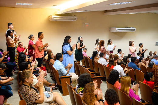 Imagem: plateia com pessoas em pé e outras sentadas em auditório