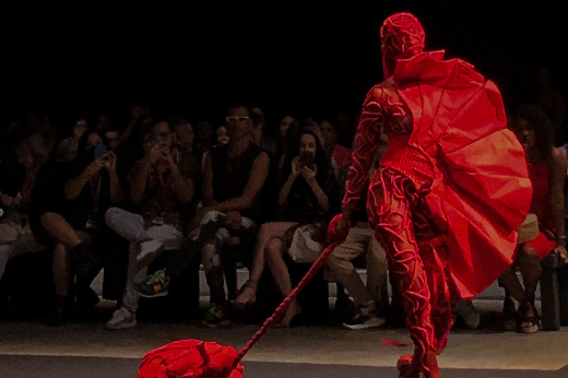 Imagem: modelo vestida de vermelho desfila em passarela