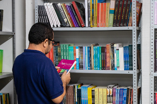 Imagem: homem observando livros em uma prateleira 