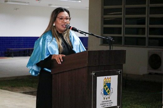 Imagem: Professora discursa no púlpito durante a colação, com veste talar azul