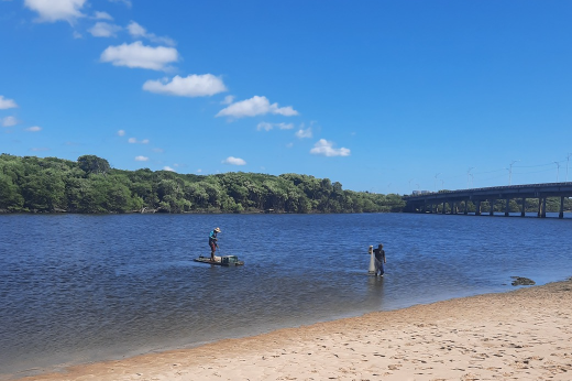 Imagem: Dois pescadores no Rio Ceará. Ao fundo, é possível ver a ponte sobre o rio