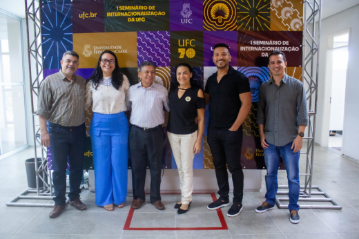 Imagem: Participantes posam em frente a banner do 1º Seminário de Internacionalização da UFC