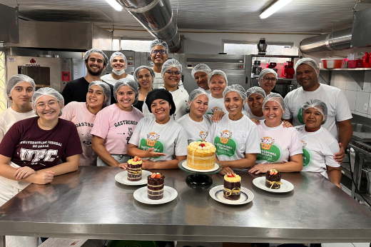 Imagem: alunos e alunas do curso de Gastronomia posam atrás de uma mesa com bolos decorados